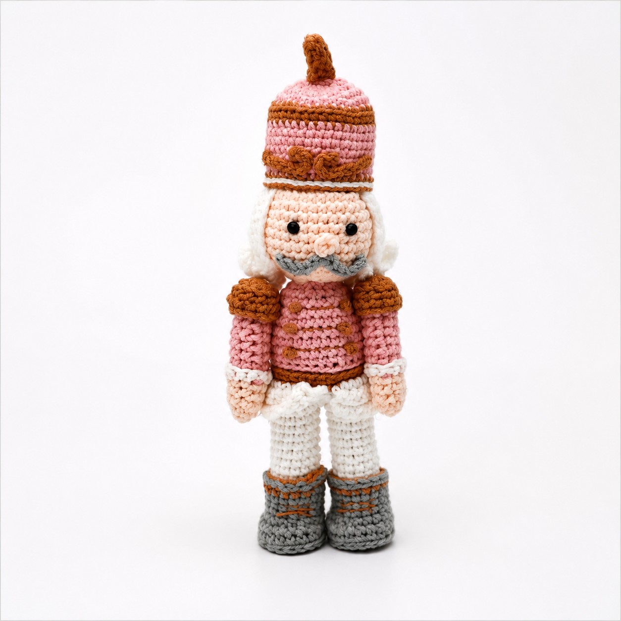 Gehaakte notenkraker in roze van 25 cm met hoge muts, witte broek en grijze laarsjes.