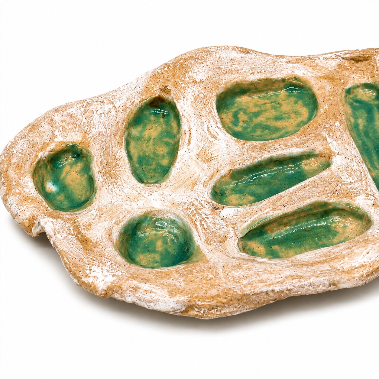 Detail handgemaakte tapasschaal met groene geglazuurde vakjes