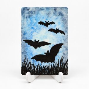 Handbeschilderde Halloweenkaart Vleugels in de nacht van By Mieke met vier zwarte vleermuizen boven donker gras tegen een blauwe lucht.