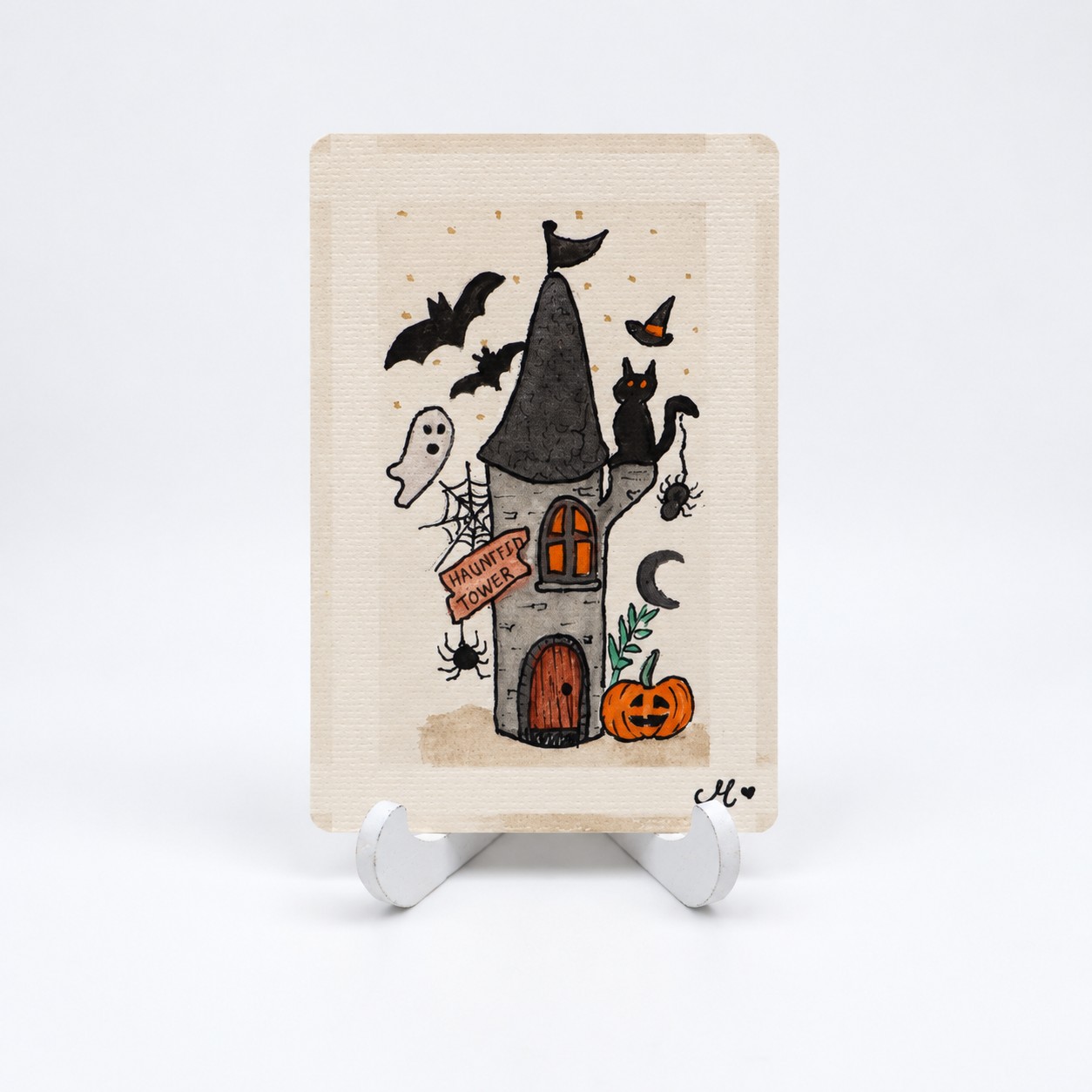 Handbeschilderde Halloweenkaart Het spookt in de toren van By Mieke met spooktoren, zwarte kat, vleermuizen en pompoen.