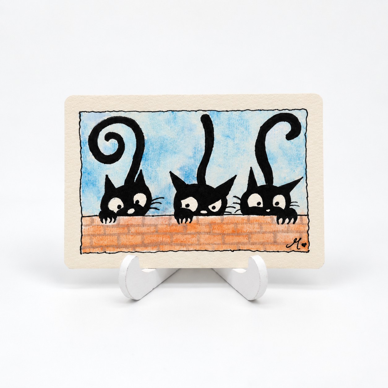 Handbeschilderde liggende aquarelkaart Drie nieuwsgierige katjes van By Mieke met drie zwarte katten achter een bakstenen muurtje.